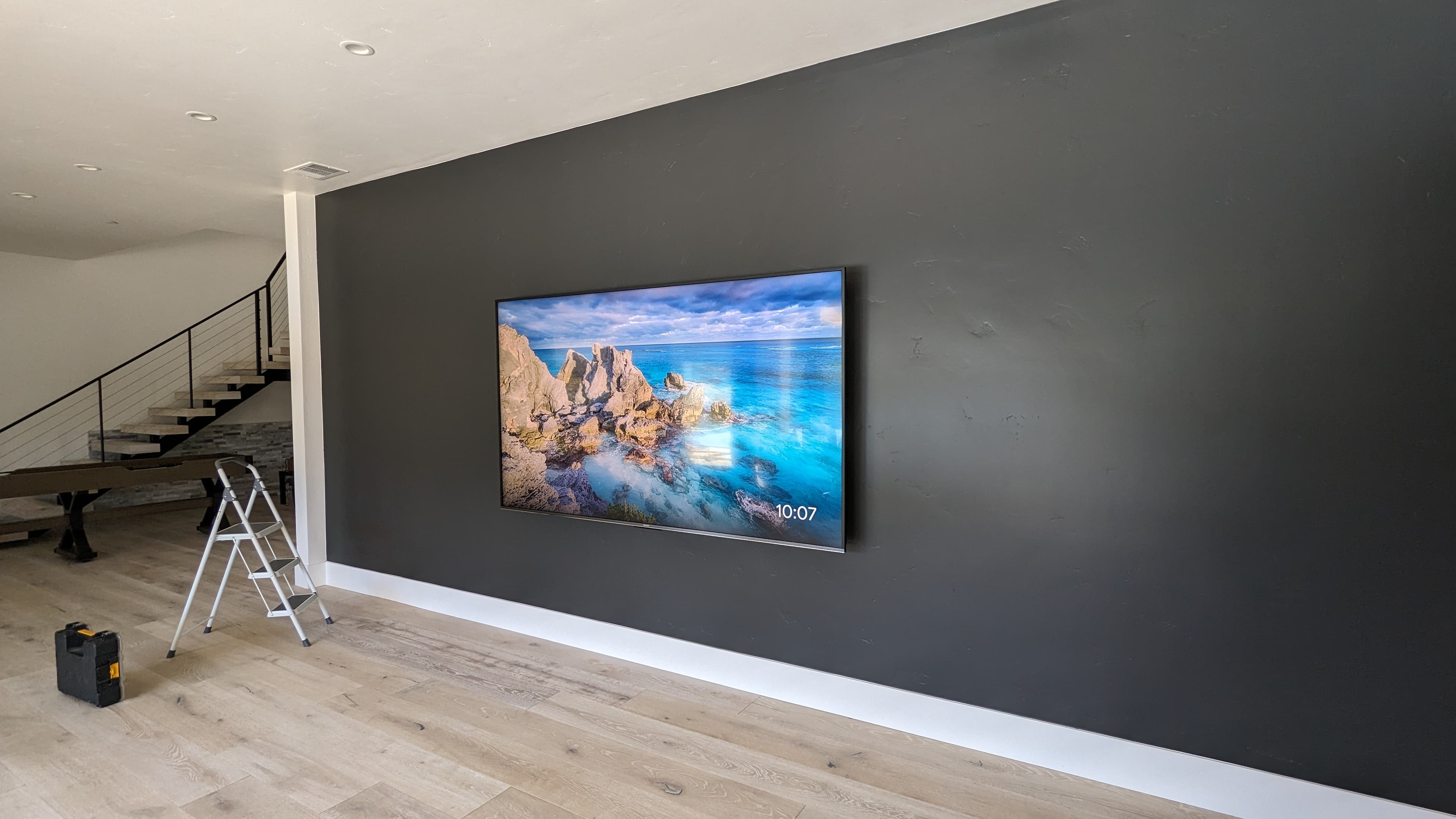 Large TV on dark accent wall with modern staircase in El Dorado Hills, CA