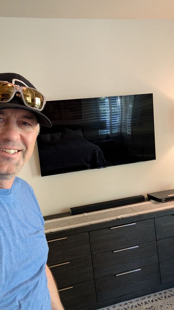Dan with TCL 65-inch TV mounted on existing wall mount with soundbar on dresser below in Camino, CA
