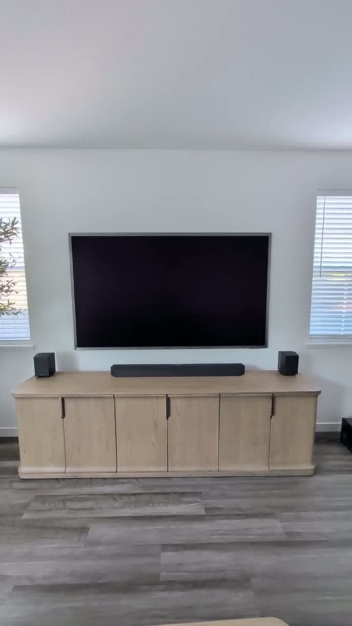 85-inch Samsung S95F OLED mounted flush between two windows with Q990F soundbar on oak credenza in Granite Bay, CA