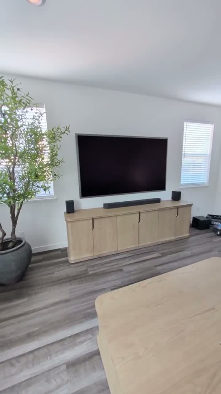 Viewing angle from seating area showing 85-inch Samsung S95F with vaulted ceiling and potted olive tree in Granite Bay, CA