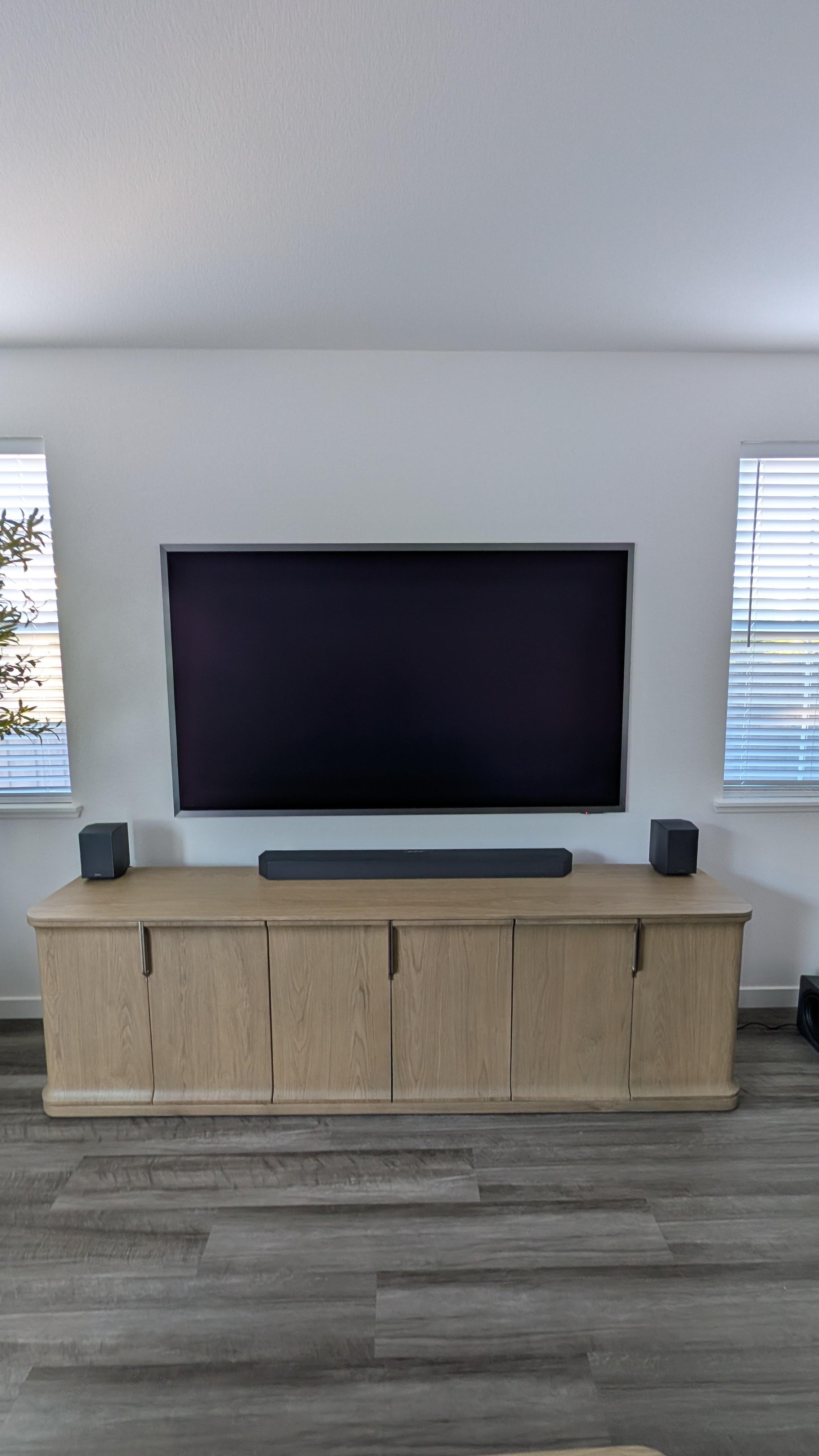 85-inch Samsung S95F OLED mounted flush between two windows with Q990F soundbar on oak credenza in Granite Bay, CA