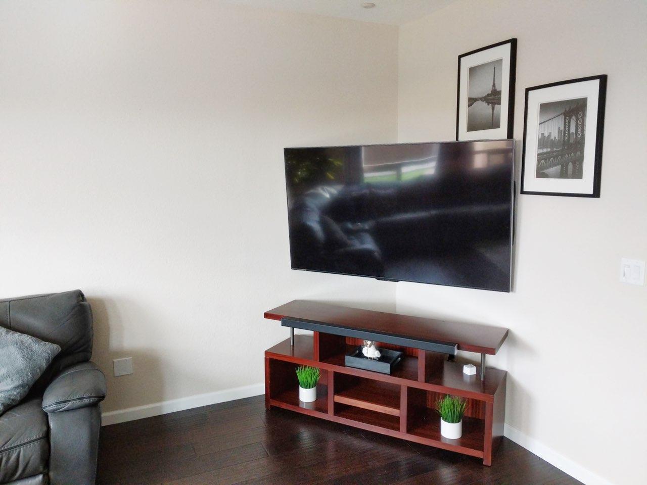 TV mounted in corner of living room on full motion arm above media console in Sacramento, CA
