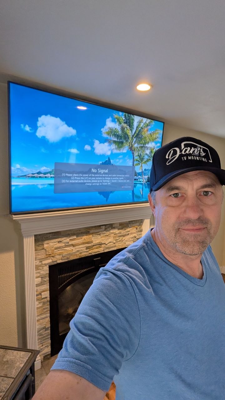 Dan with 75-inch LG TV mounted above stacked stone fireplace in Placerville, CA