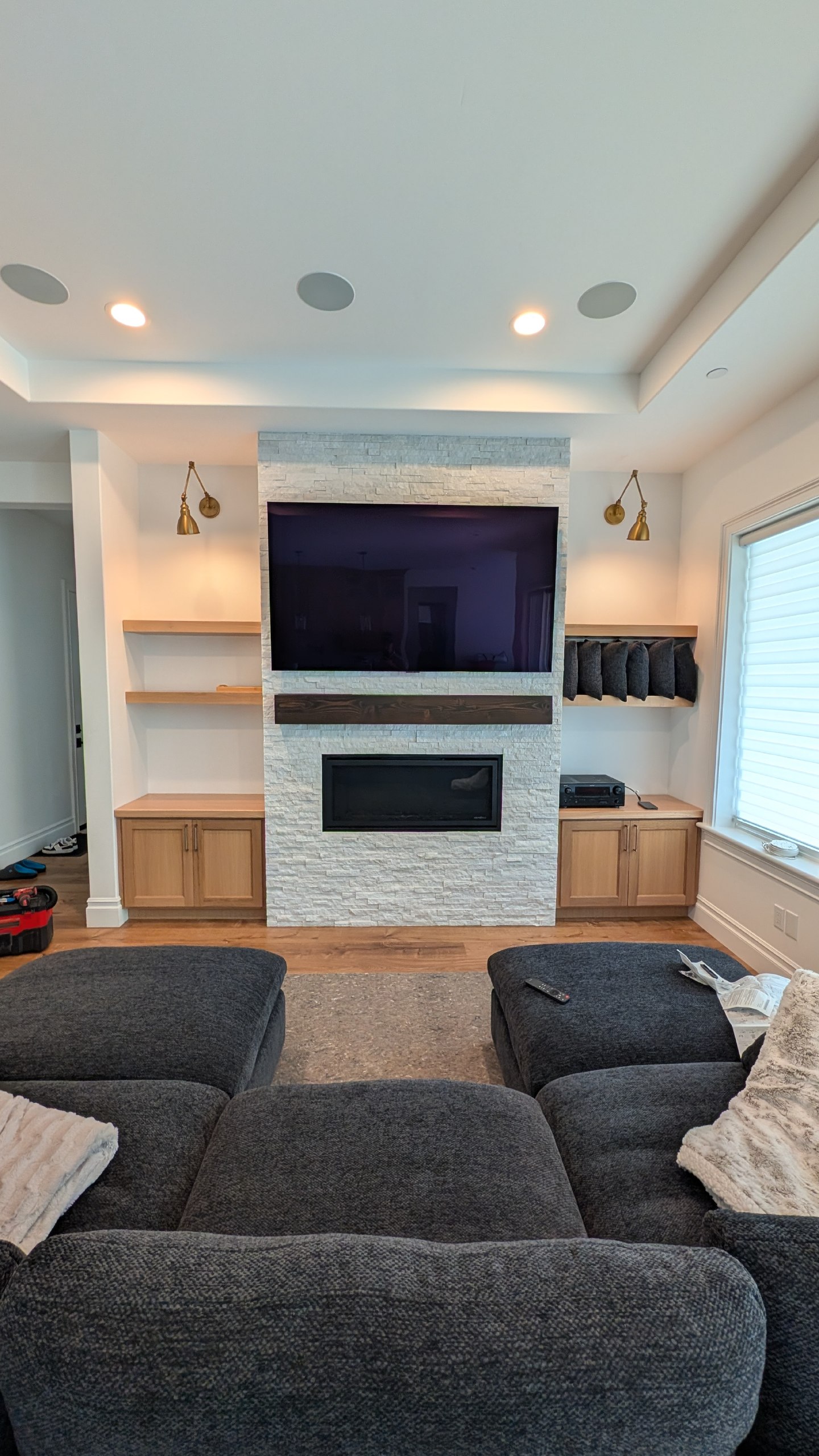 TV mounted above stone fireplace with built-in cabinetry and floating shelves in El Dorado Hills, CA