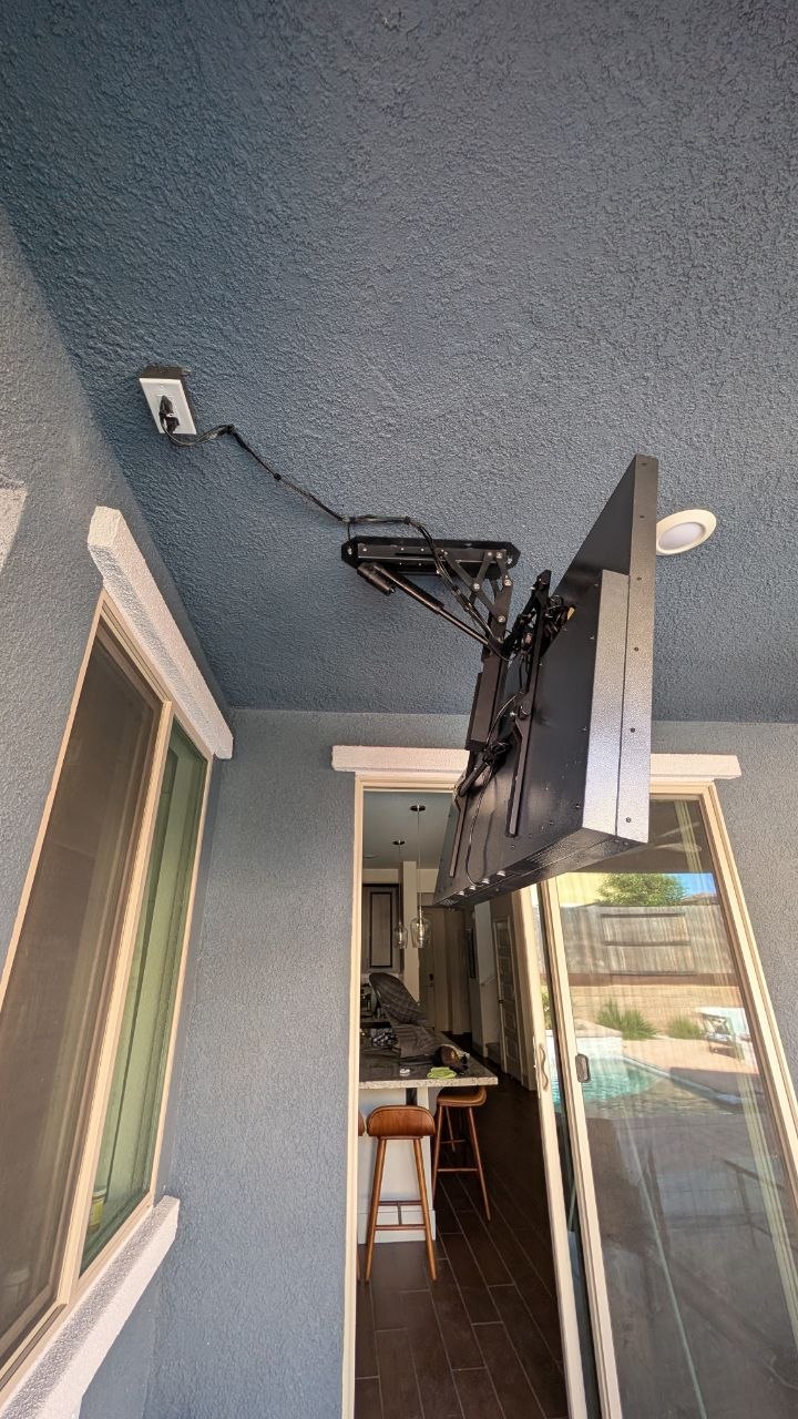 Fold-down TV mount arm deploying from stucco wall on outdoor covered patio in Rancho Cordova, CA