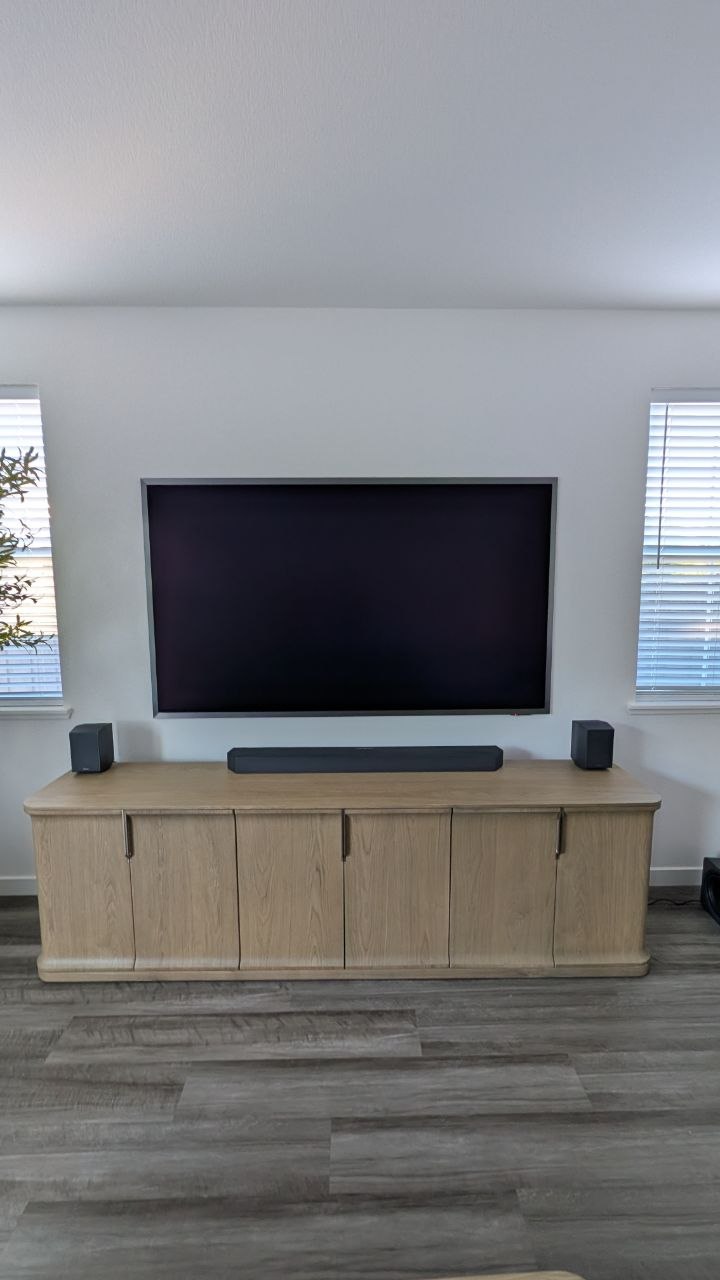 85-inch Samsung S95F OLED mounted flush between two windows with Q990F soundbar on oak credenza in Granite Bay, CA