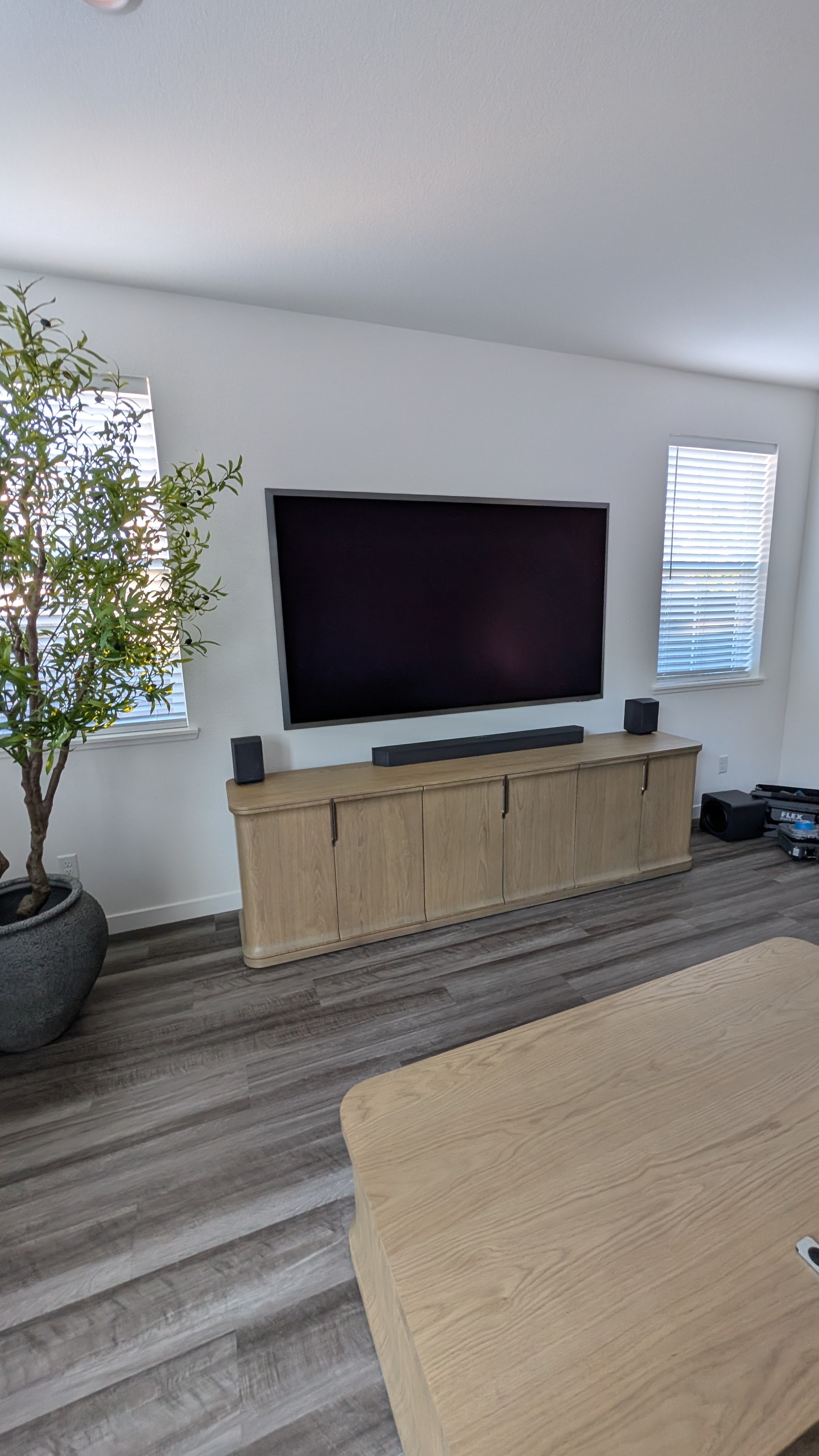 Viewing angle from seating area showing 85-inch Samsung S95F with vaulted ceiling and potted olive tree in Granite Bay, CA