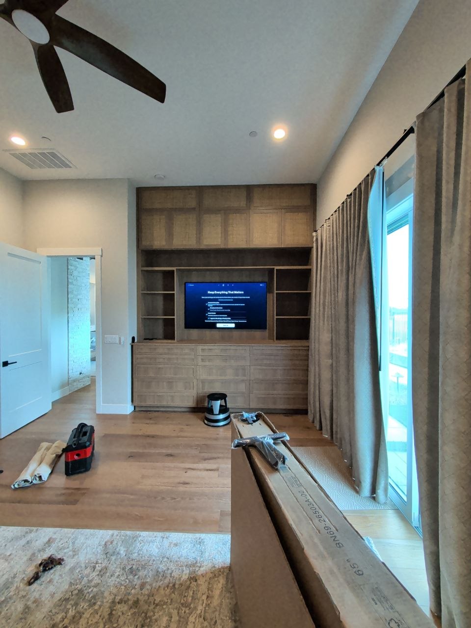 Wide room view of Samsung TV in built-in cabinet with hardwood floors and large windows in El Dorado Hills, CA